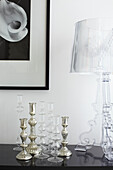 Silver and glass candlesticks with perspex lamp on sideboard in Isle of Wight home, UK