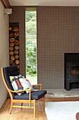 Vintage armchair and woodpile in living room of contemporary Isle of Wight new-build home UK