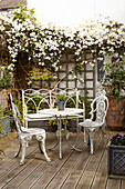 Flowering jasmine with wrought iron table and chairs on decking with trellis semi-detached home UK