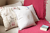 Linen cushions with pink blanket and book on sofa in semi-detached home UK