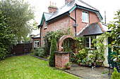Seitenweg und Rasen mit gemauertem Torbogen im Garten eines Hauses in East Cowes, Isle of Wight, Vereinigtes Königreich