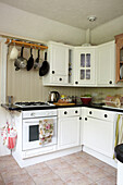 saucepans hang above gas hob in white fitted kitchen of East Cowes home, Isle of Wight, UK