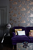 Vintage-Lampe mit lila Sofa und gemusterter Tapete in einem Londoner Wohnzimmer im Retrostil, England, UK