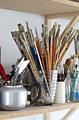 Paintbrushes and spatulas on shelf in studio of Bembridge houseboat Isle of Wight, UK