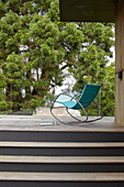 Rocking chair on timber decking with trees and view to the Solent in modern Isle of Wight home UK