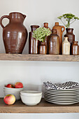 Collection of earthenware vases with apples and plates on shelves in Brighton home East Sussex UK