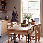 Küche im Landhausstil mit Holztisch und Katze, die im Fenster sitzt