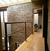 View into bathroom from mezzanine landing area with exposed brick wall and glass roof
