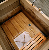 Quadratische Holzbadewanne mit Spiegelung des Oberlichts im Wasser