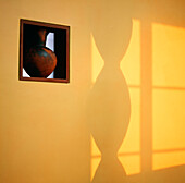 Earthenware pot displayed in interior picture window on yellow painted wall