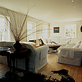 Weißes, geräumiges Wohnzimmer mit Holzdielenboden und Tierfellteppichen