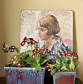 Auriculars plated in a square glazed pot in front of an oil painting of a young girl