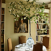 Dramatic glass vase with branch of Burkwood Viburnum on dining table