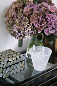 Stilleben einer rosa Hortensie mit dekorativem Kasten und Milchglas