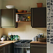 Kitchen with dark green units and beige wall tiles