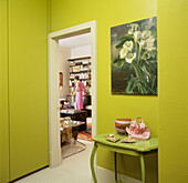 Frau geht von einem auffallend grün dekorierten Flur durch die Tür ins Wohnzimmer