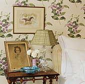 Bedroom detail with pretty floral pattern wallpaper and bedside table