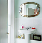 Hellblaues und weißes Badezimmer mit weißem Standwaschbecken und Spiegel mit Beleuchtung