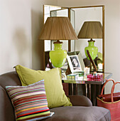 Room corner with mirrored table, screen and bright green glass table lamp and glass objects