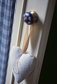 Close up of embroidered heart shaped sachet on blue door knob