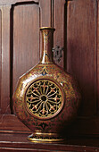 Close up of ornate chinoiserie vase against wooden cabinet