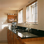 Kitchen sink by windows with black granite worktop and cherry wood units