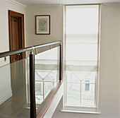 Langes Fenster mit Jalousie auf dem Treppenabsatz mit glasgetäfelter Balustrade