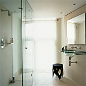 Badezimmer aus Kalkstein mit Glasduschtür, Glaswaschbecken und Spiegel