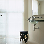 Badezimmer aus Kalkstein mit Glasduschtür und Glaswaschbecken