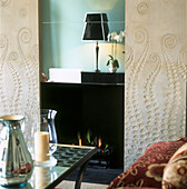 Verspiegelter Kamin mit dekorativer Einfassung aus geätztem Stein in einem eleganten Wohnzimmer mit Sofa und Couchtisch