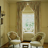 Window setting two Victorian nursing chairs in beige and white master bedroom