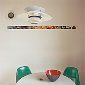 Close up of ceiling light with two light green fibre-glass chairs around kitchen table