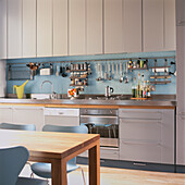 Fitted kitchen in pale grey and stainless steel with light blue mosaic splashback