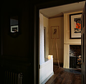View of cream panelled bathroom with fire grate from dark corridor with wood panelling