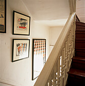 White stairwell with horse guard prints and cardinal red painted stair treads