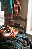 Still life of vintage ladies leather shoes tartan throw and ladder back chair