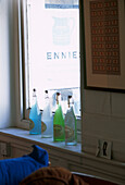 Line of blue and green bottles in a window in living room 