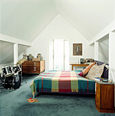 White attic bedroom under sloping eaves with drum kit plan chest and double bed