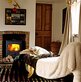Fake fur throws and exotic textiles on chaise lounge in country cottage