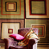 Detail of geometric wall hanging and purple velvet armchair
