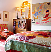 Brightly coloured bedroom adorned with fairy lights and printed fabrics