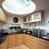 Angled kitchen with dome glass roof black granite worktops wooden units and stainless steel splash backs 