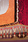 Close up trimmings and beaded fringe edging on fabric covered cabinet 