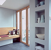 Wood framed patio doors and boxed shelving unit with modern bench seating in white kitchen