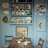 Mit dekorativem Porzellan gefüllte Wandkommode in einer hellblauen Küche im Landhausstil