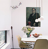 Corner of dining room with original fibreglass Eames chairs around white dining table and low ceiling lights 