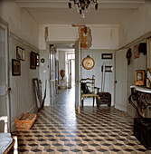 Entrance hall of chateau with original black and white stone checked floor painted wood panelled walls and vintage furniture
