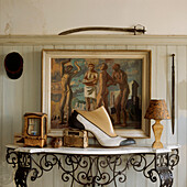 marble top side table with cast iron ornate legs with collection of ornaments in a hallway with painted panelled walls