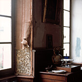 Peeling wallpaper and crumbling plaster on walls in an old chateau study
