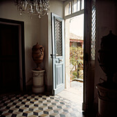 Entrance hall of a period French chateau with open double front doors and checked stone floor